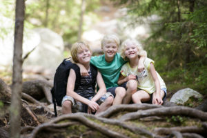 Kolme iloista lasta metsässä.
