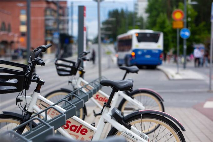 Kaupunkipyöriä nojaa telineeseen jalkakäytävällä.