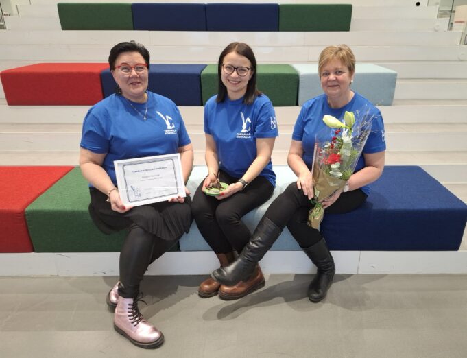 Otsonmäen päiväkodin tiimi istuu kirjaston portailla palkintojen kera.