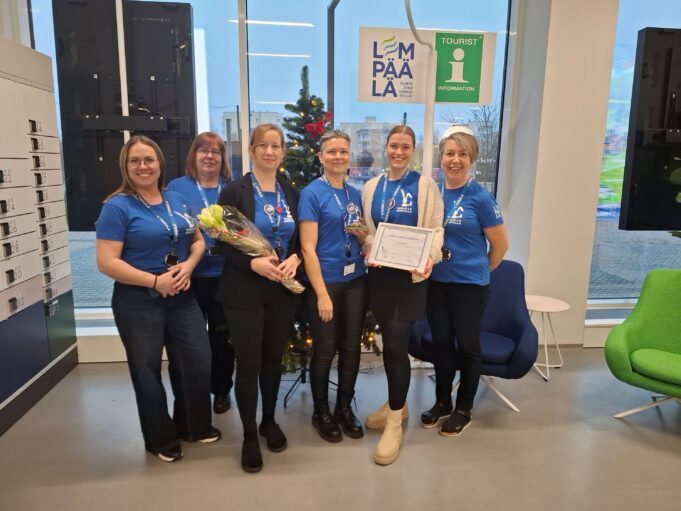 Palvelukäytävän tiimi seisoo joulukuusen edessä käsissään Tarkalla korvalla -palkinnot.