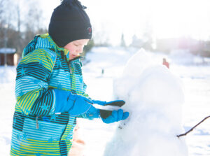 Lapsi tekee lumiukkoa.