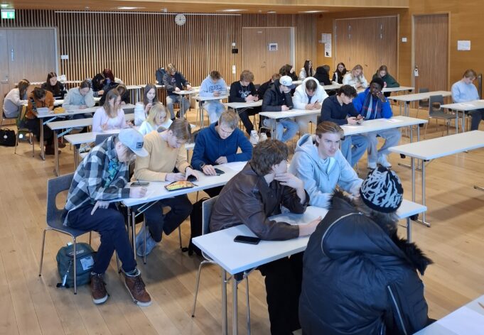 Joukko nuoria istuu luentosalissa keskustelemassa ja tekemässä ryymätehtävää.