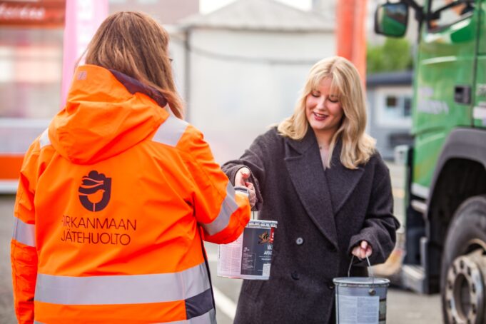 Ihminen antaa maalipurkin toisella ihmiselle