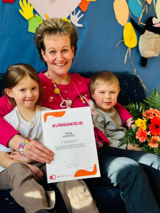 Tarja lasten keskellä kunniakirjan kanssa.